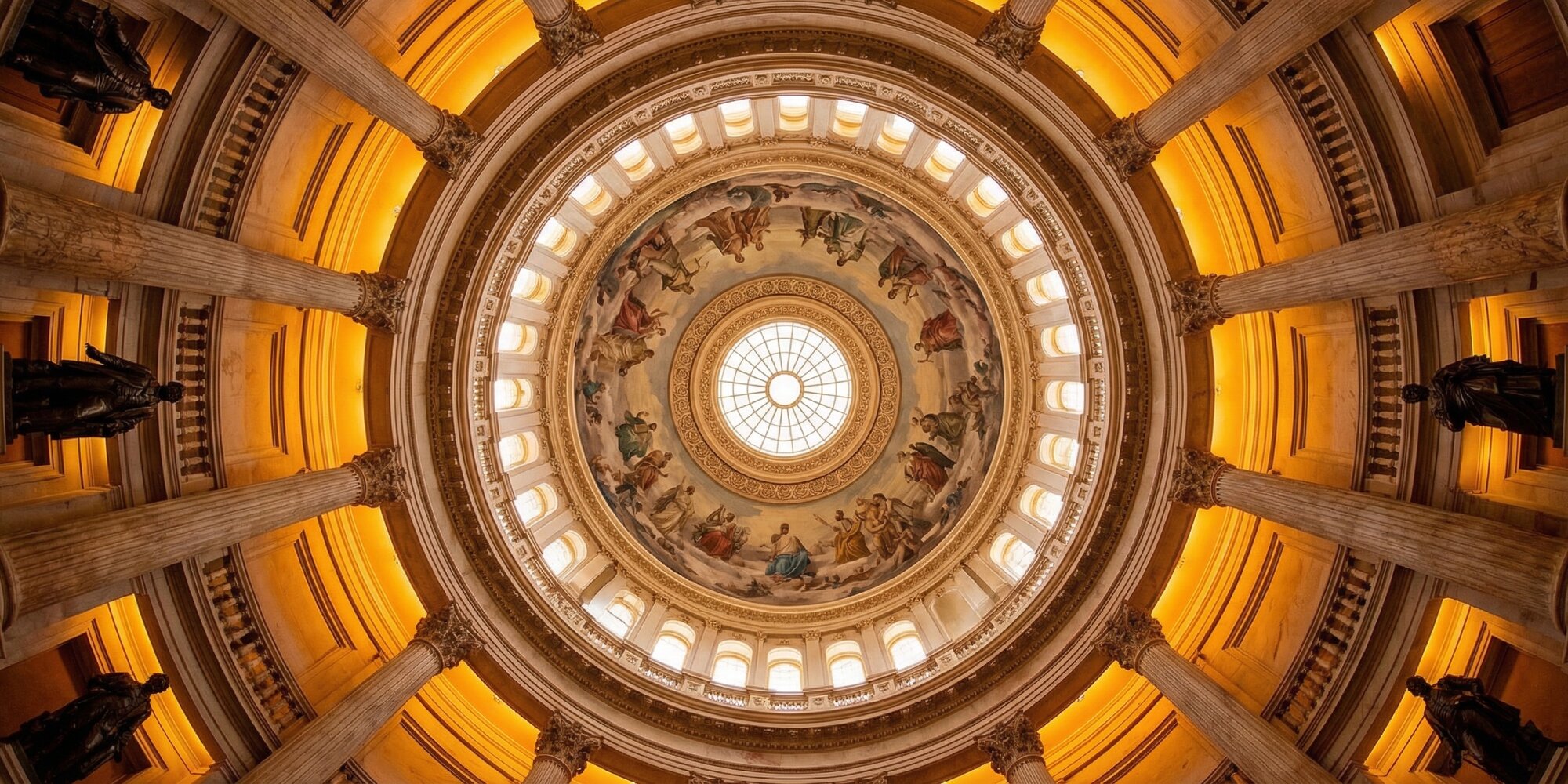 Interior of the U.S. Capitol rotunda viewed from below, ornate stone rings converging toward a central ceiling oculus